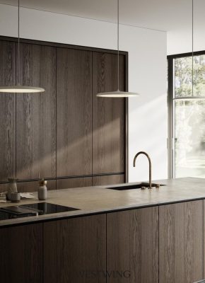 Virtuvės sala su tamsaus medžio apdaila, minimalistiniu stalviršiu ir auksiniu maišytuvu. Pro langą sklinda natūrali šviesa, o virš salos kabo modernūs šviestuvai.